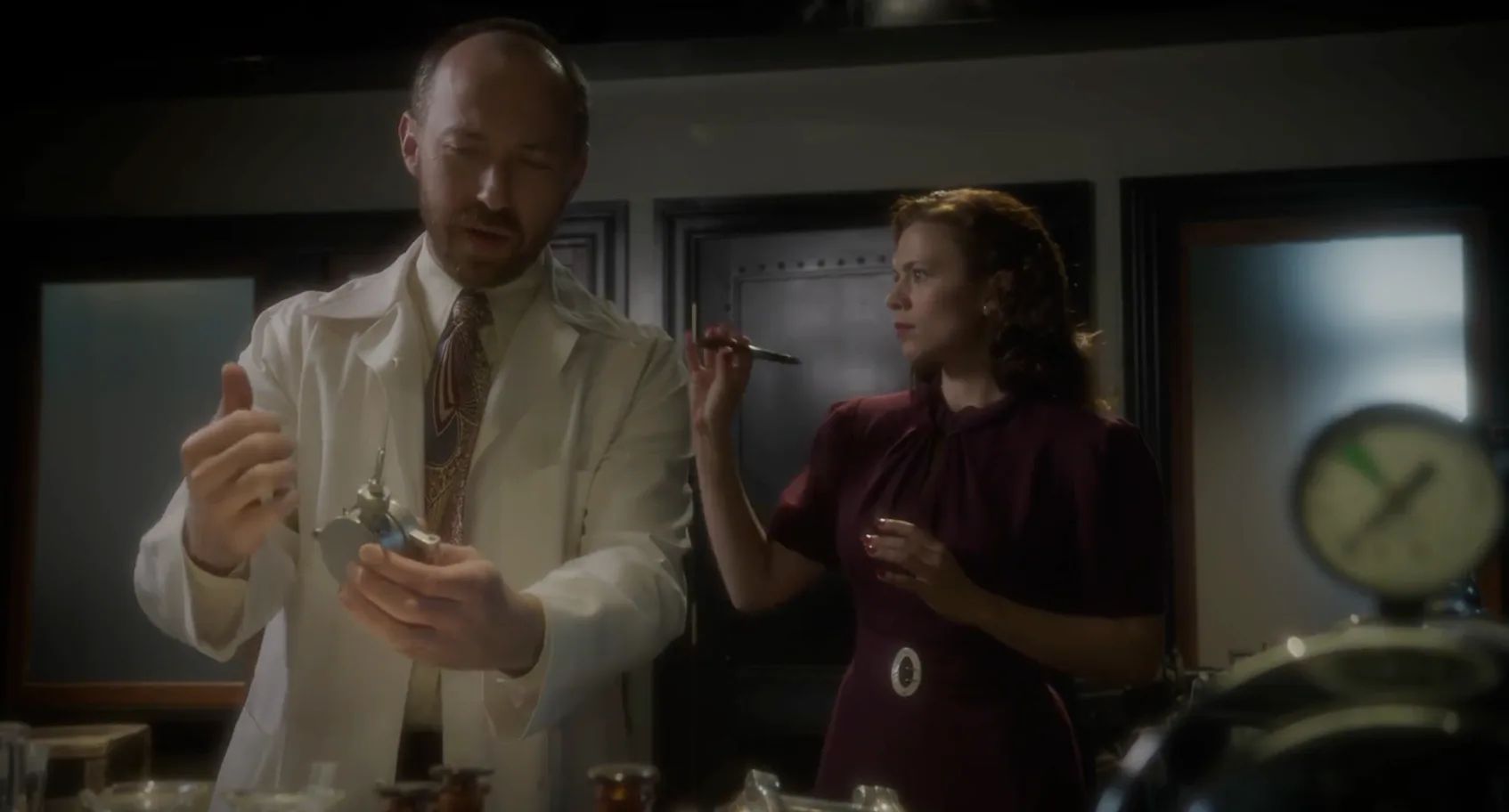 Agent Doobin Perplexes Over a Stark Device as Peggy Loudly Takes Pictures